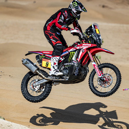 Jezdec rallye Dakar na motocyklu Honda v poušti.