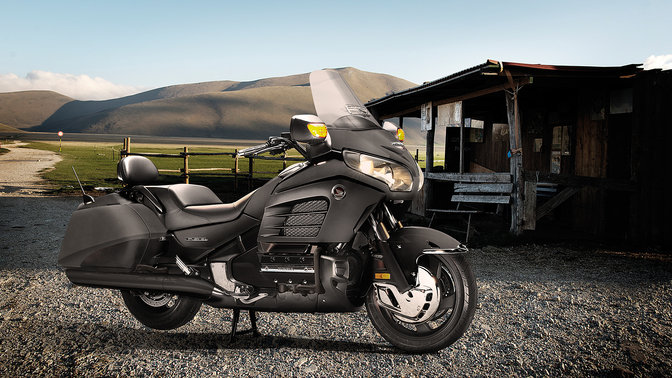Front 3-quarter view of Gold Wing F6B parked with rider leaning on it. (rural location).