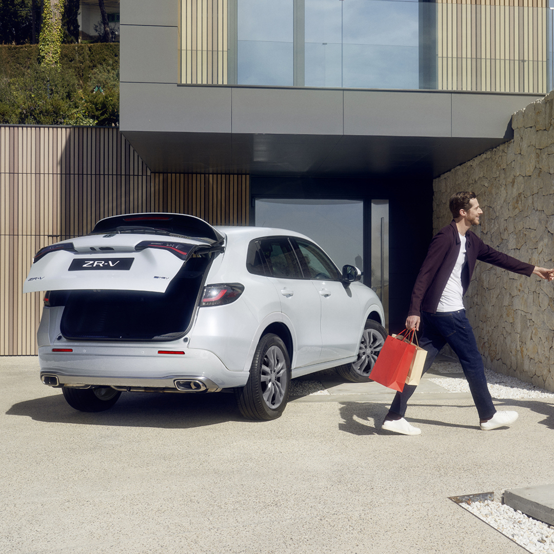 Bílý vůz ZR-V na příjezdové cestě s elektricky ovládanými dveřmi zavazadlového prostoru