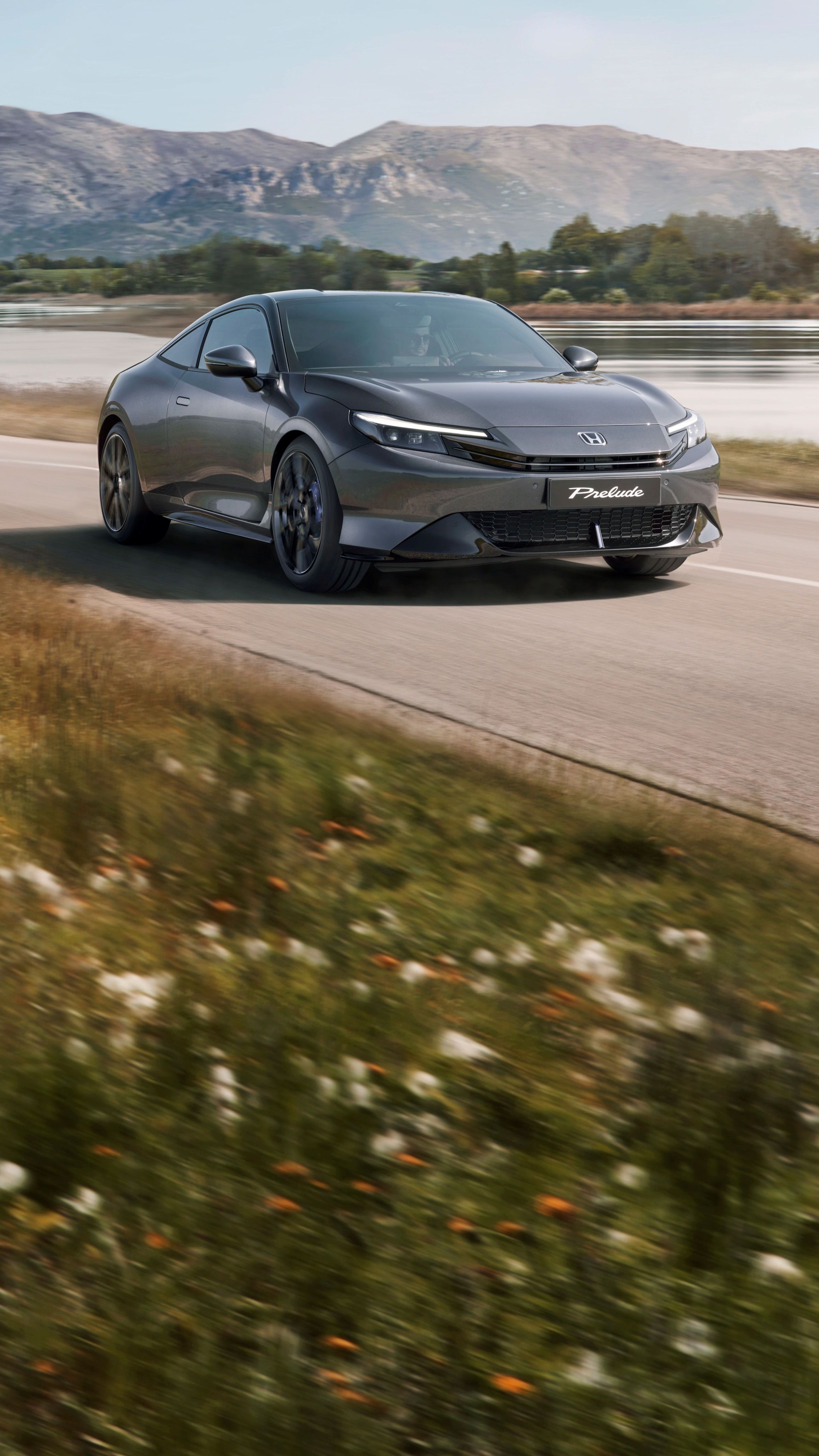 Honda Prelude v barvě Crystal Black Pearl jedoucí po klikaté silnici s otevřenou krajinou v pozadí.