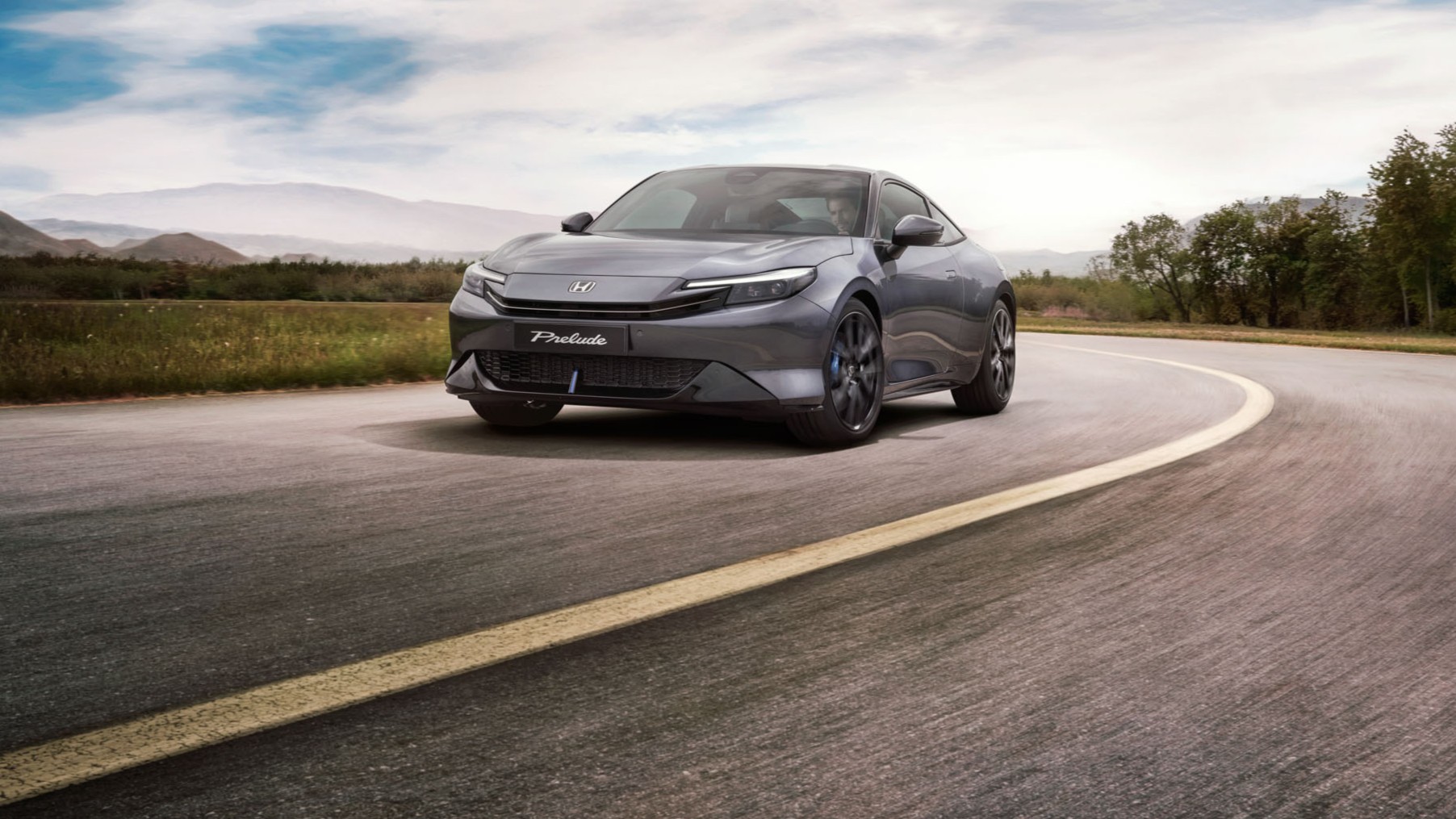 Honda Prelude v barvě Crystal Black Pearl jedoucí po klikaté silnici s otevřenou krajinou v pozadí.