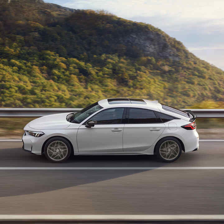 Honda Civic Hybrid v pohybu na dálnici s výhledem na krajinu.