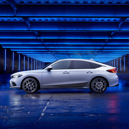 Boční pohled na Honda Civic e:HEV zaparkovaný v postranní ulici.