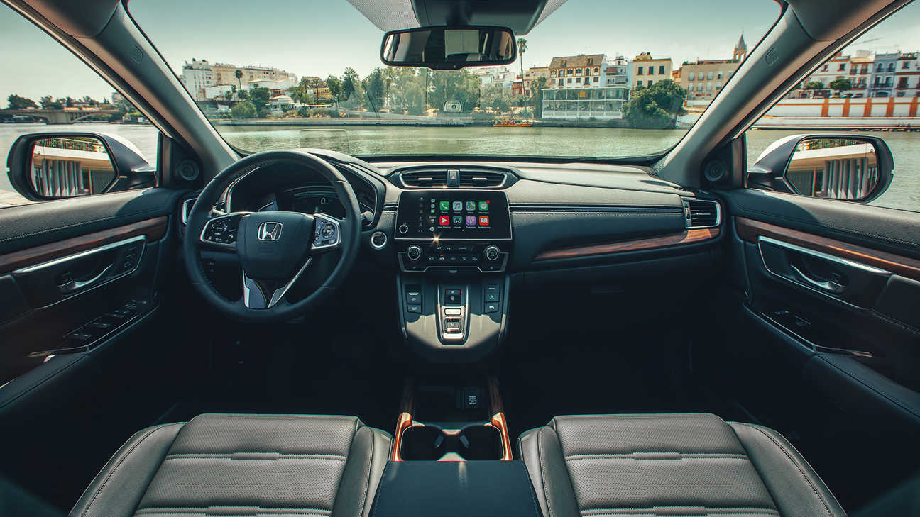 Pohled na palubní desku v interiéru vozu Honda CR-V Hybrid se širokým výhledem na ulici