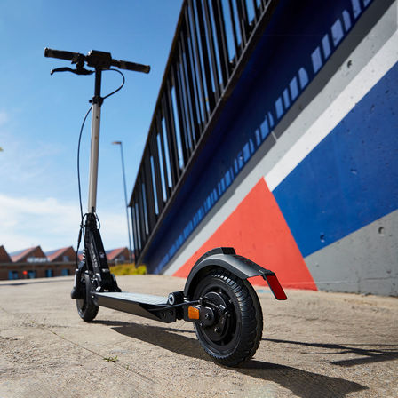 Pohled na zaparkovanou koloběžku eSYMO u pestře pomalované zdi