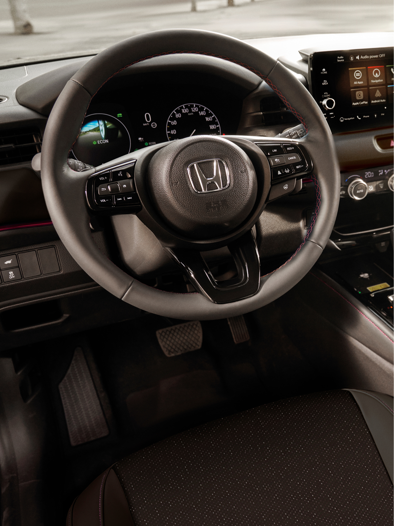 Pohled do interiéru vozu Honda HR-V s volantem, digitálním přístrojovým panelem, středovým dotykovým displejem a voličem automatické převodovky.