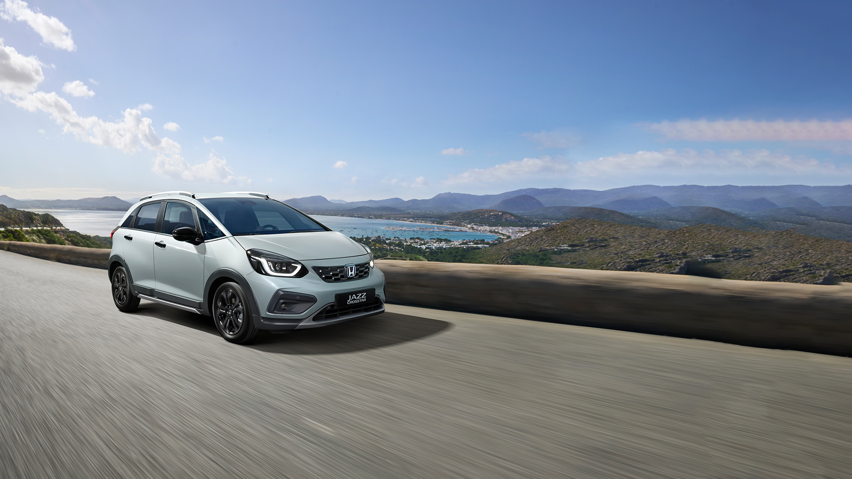 Přední 3/4 pohled na model Honda Jazz Crosstar jedoucího na silnici u pobřeží 