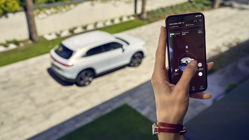 Dáma stojící vedle bílého vozidla Honda e používající aplikaci My Honda+