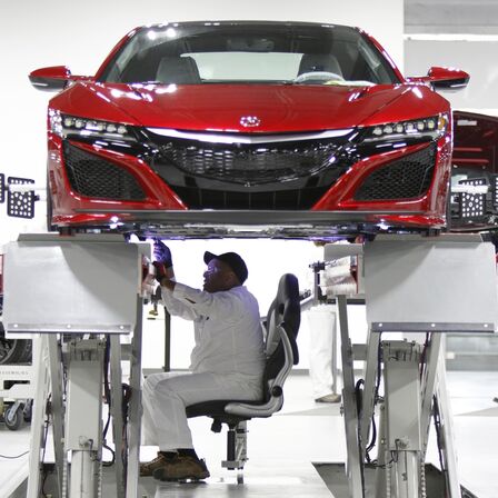 Pohled zepředu na vůz NSX, na kter&eacute;m pracuje mechanik společnosti Honda