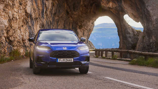 Modré sportovní hybridní SUV ZR-V při jízdě po horských silnicích.
