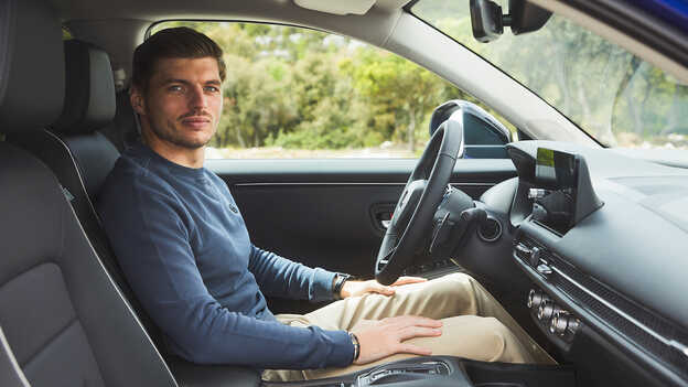 Max Verstappen sedí v hybridním SUV ZR-V na parkovišti.