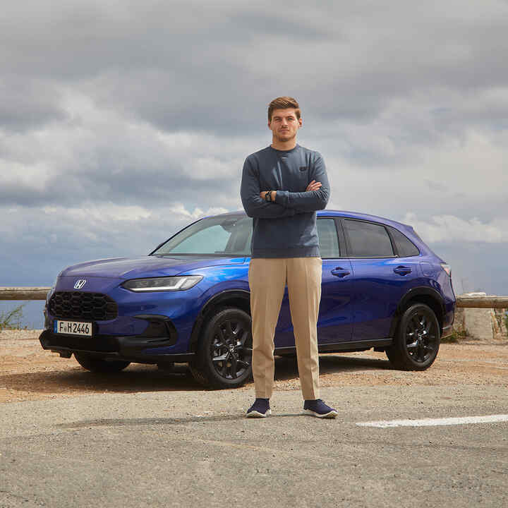 Max Verstappen vedle hybridního SUV Honda ZR-V v modré barvě.