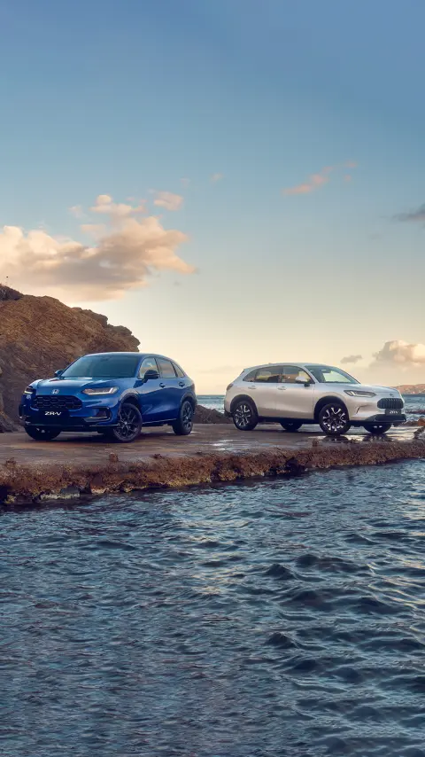 Tříčtvrtinový pohled zepředu na dva vozy ZR-V Hybrid zaparkované v horách
