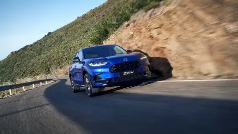 Honda ZR-V Hybrid SUV jedoucí po silnici horskou oblastí
