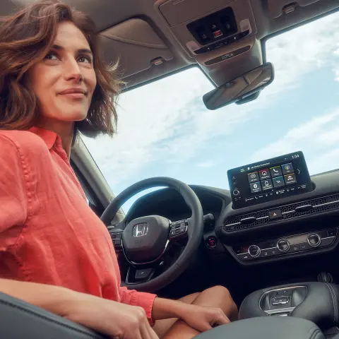 Žena sedící na sedadle řidiče a ovládající obrazovku multimediálního systému vozu Honda ZR-V Hybrid