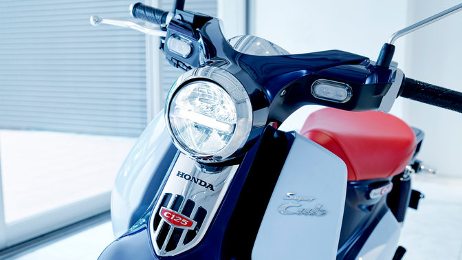 Model Honda Super Cub zaparkovaný v moderním prostředí.