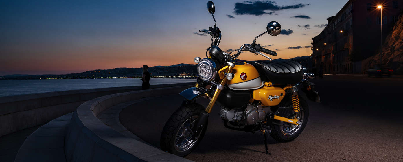 Motocykl Honda Monkey zaparkovaný na pláži.