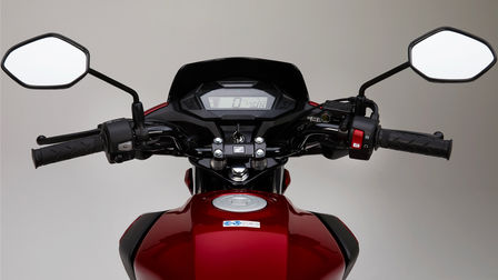Model Honda CB125F v červeném provedení, studiový snímek, zaostřeno na LCD displej