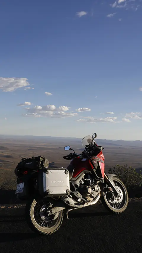 Motocykl Honda CRF1000L Africa Twin zaparkovaný na silnici s výhledem na poušť Karoo.