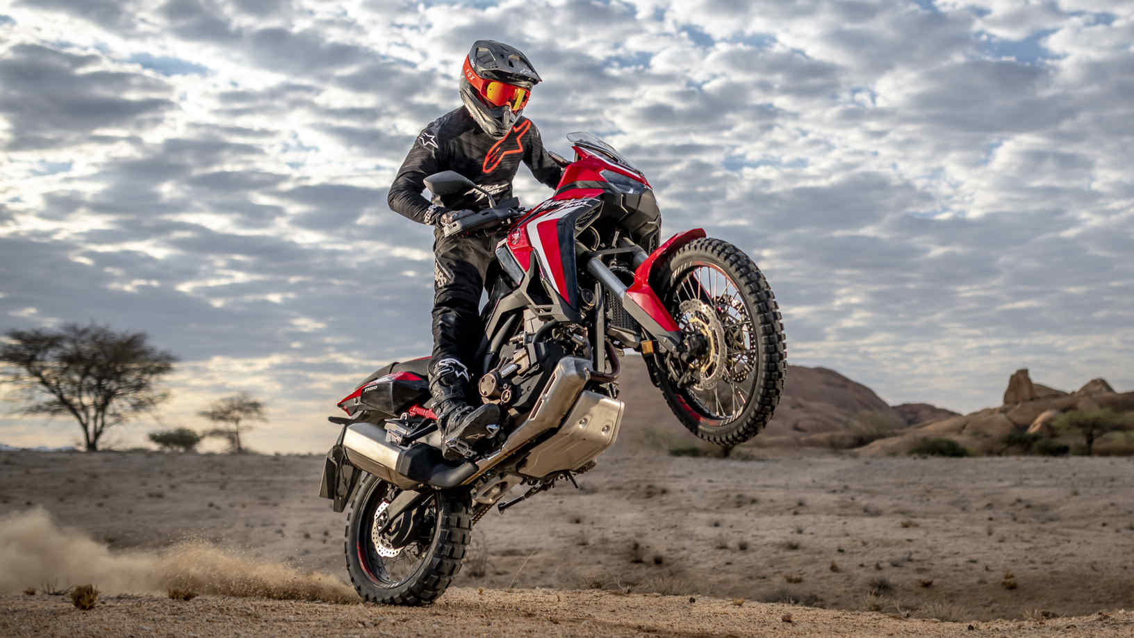 Honda Africa Twin, přední pravý poloprofil, jízda na zadním kole pouštní krajinou