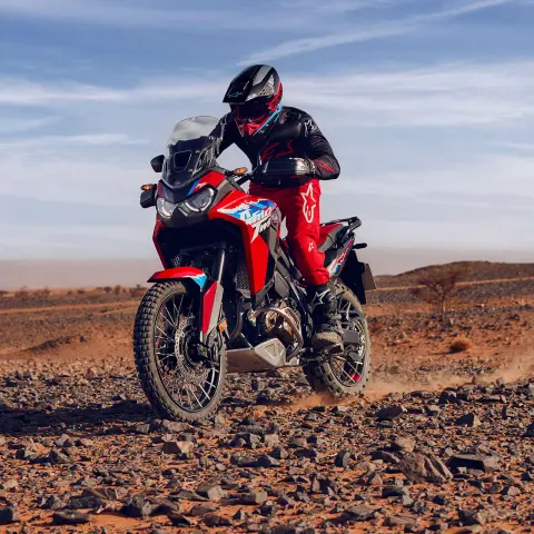 Figurant jedoucí na motocyklu CRF1100L Africa Twin skalnatým terénem v poušti