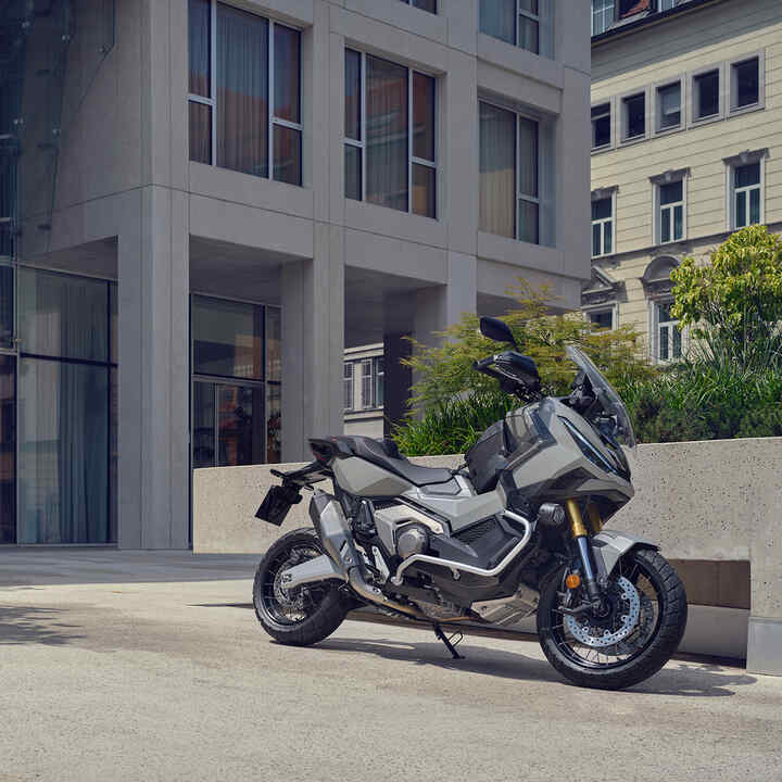 Motocykl X-ADV zaparkovaný na příjezdové cestě ve městě.