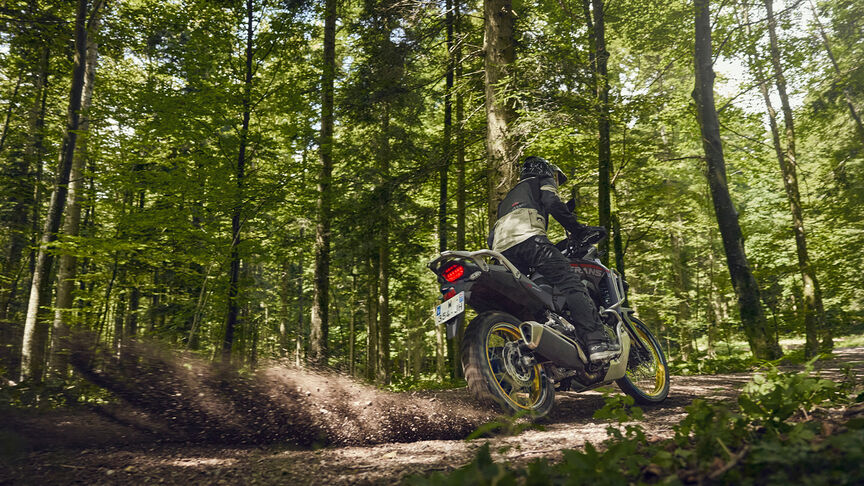 Figurant jedoucí na motocyklu XL750 Transalp v lese
