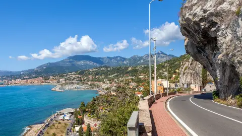 Malebná cesta pod modrou oblohou podél pobřeží Středozemního moře na francouzsko-italské hranice.