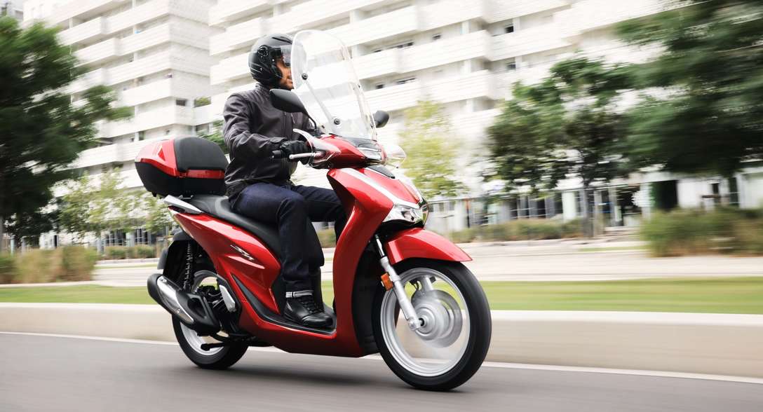 Honda SH125i, pravý přední poloprofil, s jezdcem, ve městě
