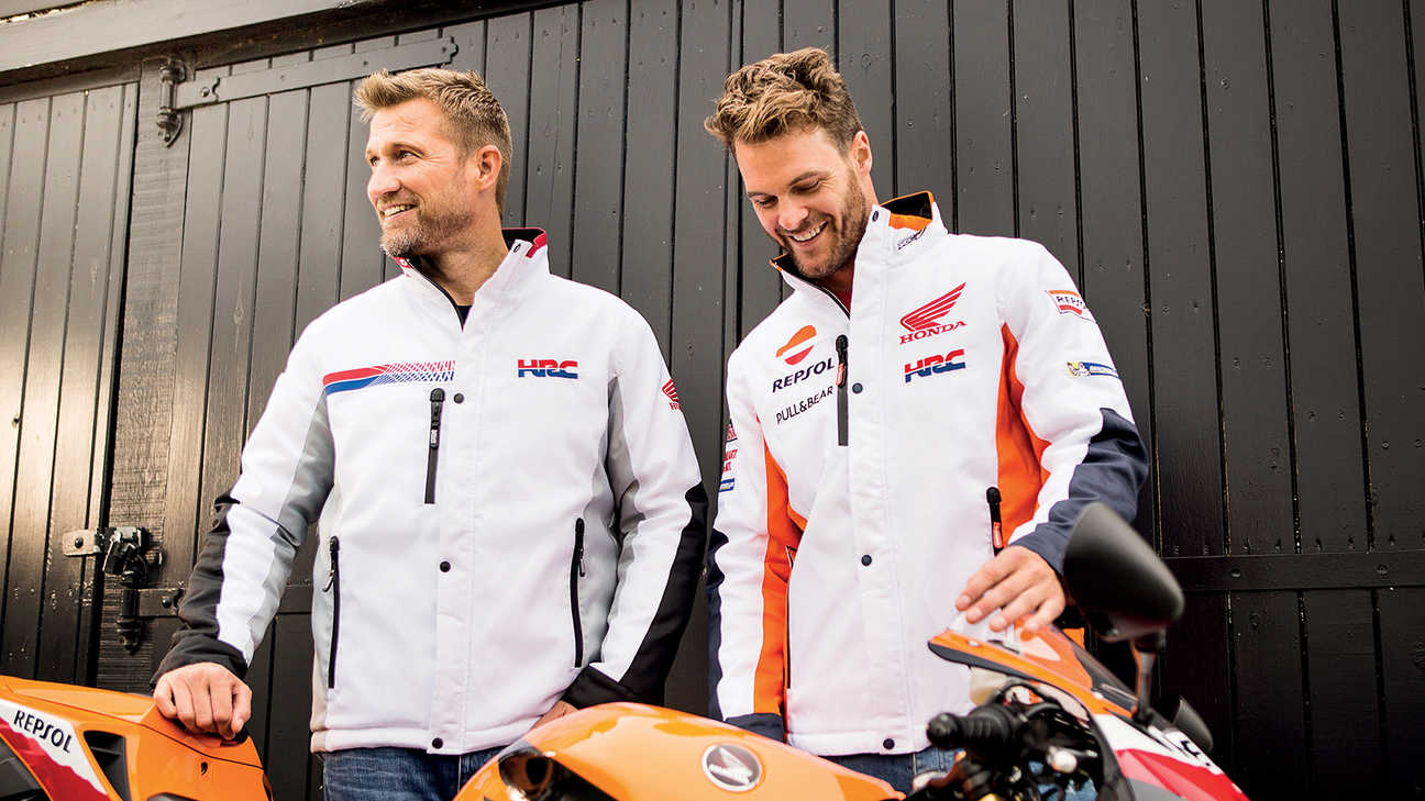Dva usmívající se muži v bílých závodních bundách Honda