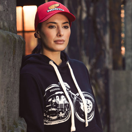 Žena v retro mikině Honda s kapucí a čepicí. 