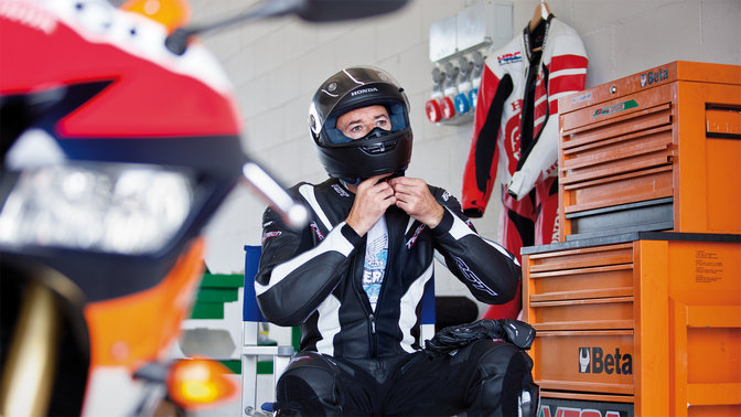 Jezdec MotoGP v helmě a motocyklistickém oděvu.