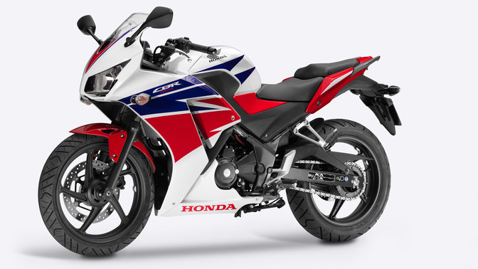 Pohled na motocykl Honda ze strany v červené, bílé a modré barvě.