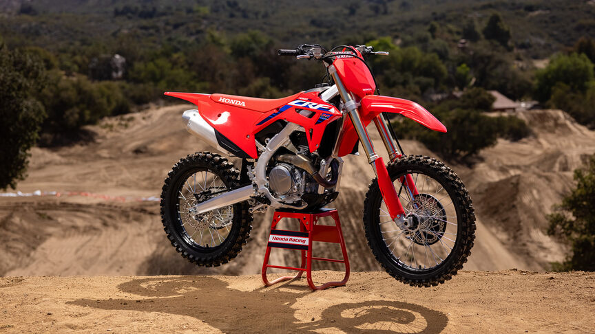 Dva jezdci překonávají skokánky na modelu Honda CRF450R.