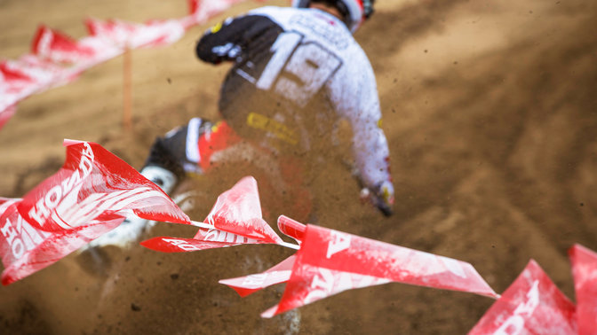 Rear view of rider on off road motorcycle. Tilted slightly to his right. Dirt track location.
