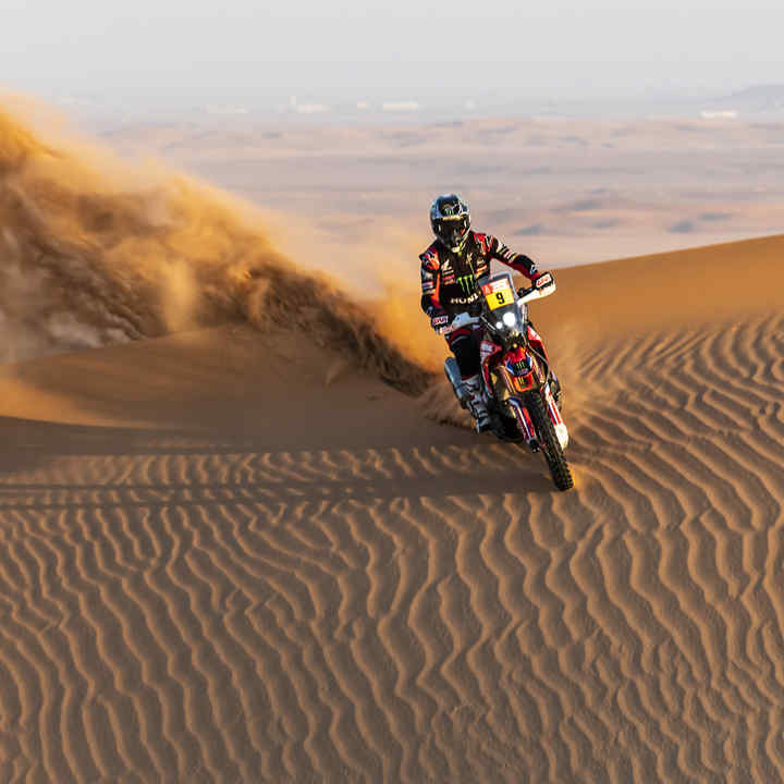 Jezdec rallye Dakar na Hondě v pouštních dunách. 
