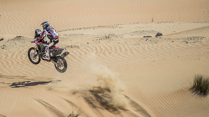 Zadní tříčtvrtinový pohled na motocykl CRF450 jedoucí písečnými dunami