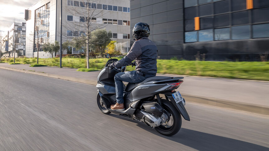 Honda PCX125 – Tříčtvrtinový dynamický snímek zezadu s jezdcem