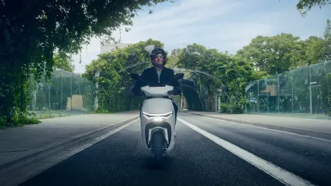 Přední pohled na figuranta jedoucího na motocyklu Honda CUV e: ve městě