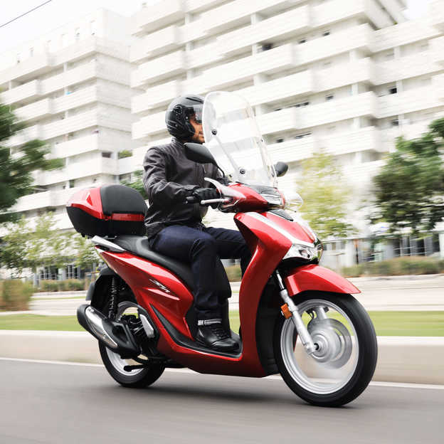 Honda SH125i, pravý přední poloprofil s jezdcem ve městě