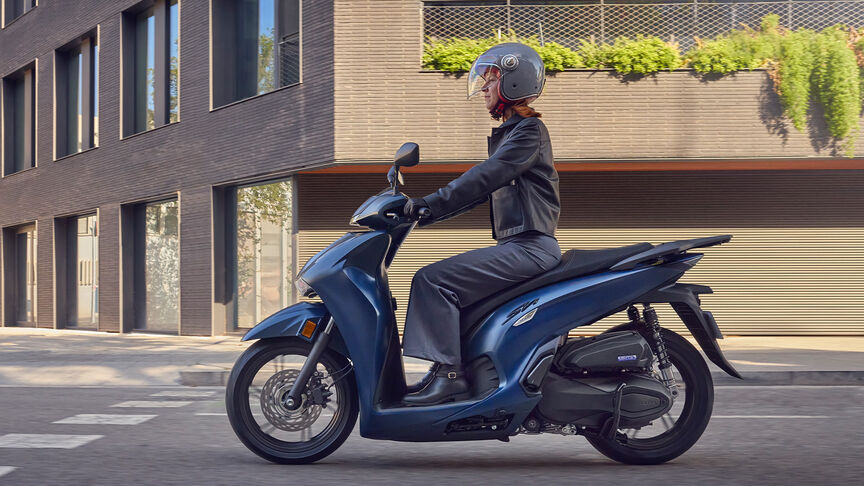 Boční pohled na dámu jedoucí na skútru Honda SH350i ve městě