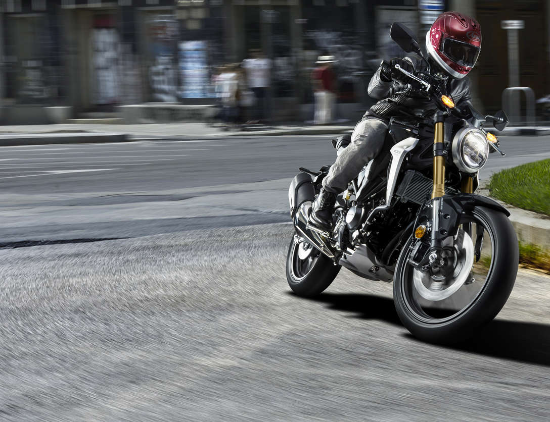 Přední tříčtvrtinový pohled na model Honda CB300R Neo Sports Café při jízdě ulicemi.