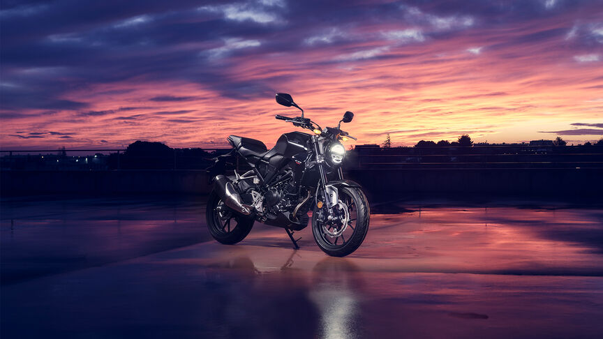 Tříčtvrtinový pohled zepředu na stroj Honda CB300R ve studiu, který si prohlíží žena.