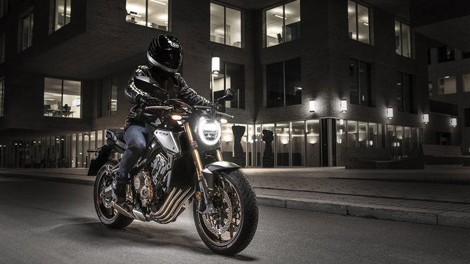 CB650R Neo Sports Café, přední pravý poloprofil, s jezdcem, ve městě za tmy