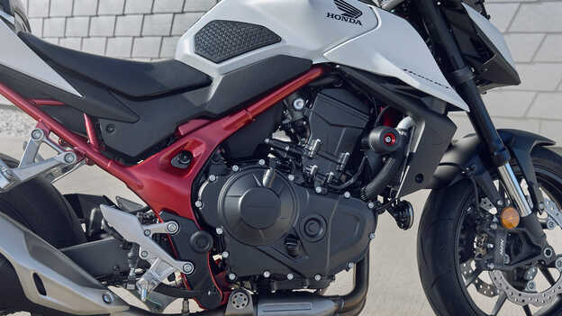 Honda CB750 Hornet s mužem opřeným o budovu.