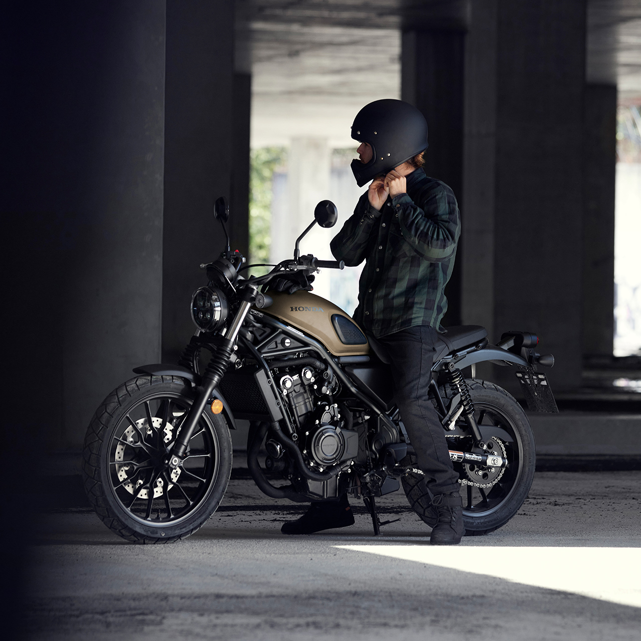 Jezdec sedící na motocyklu Honda CL500 si upravuje přilbu.