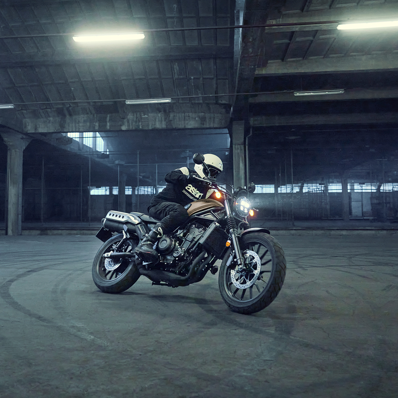 Figurant jedoucí na motocyklu Honda CL500 na parkovišti.
