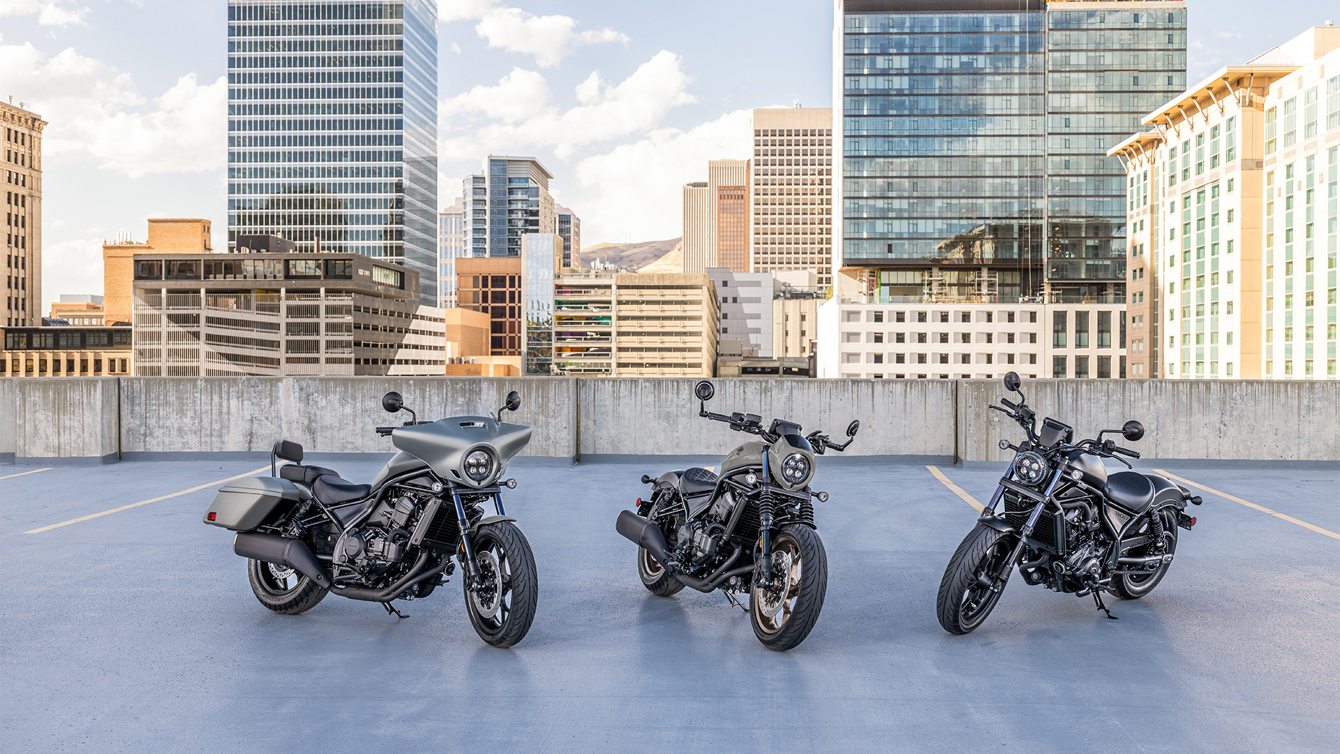Tři motocykly CMX1100 venku před moderními budovami.