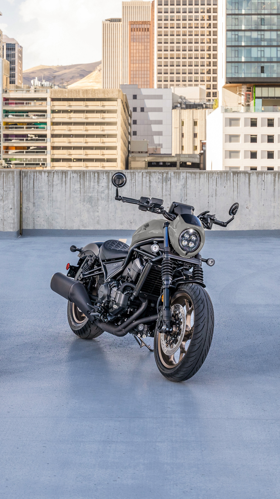 Motocykl CMX1100 venku před moderní budovou.