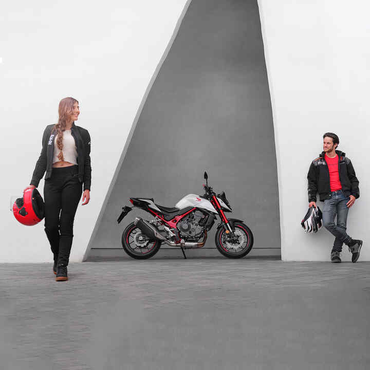 Muž a žena se opírají vedle modelu Honda CB750 Hornet.